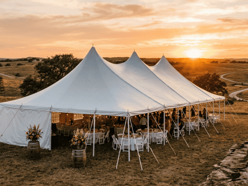 High peak pole tent rental at sunset with wedding reception setup in a Texas ranch field — Boot & Barrel Event Co. serving Cleburne and Johnson County