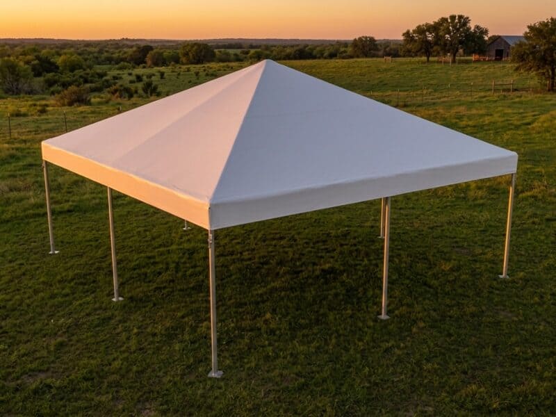 Aerial view of a 20x20 premium frame tent rental in Godley TX set up empty on a green ranch pasture at sunset