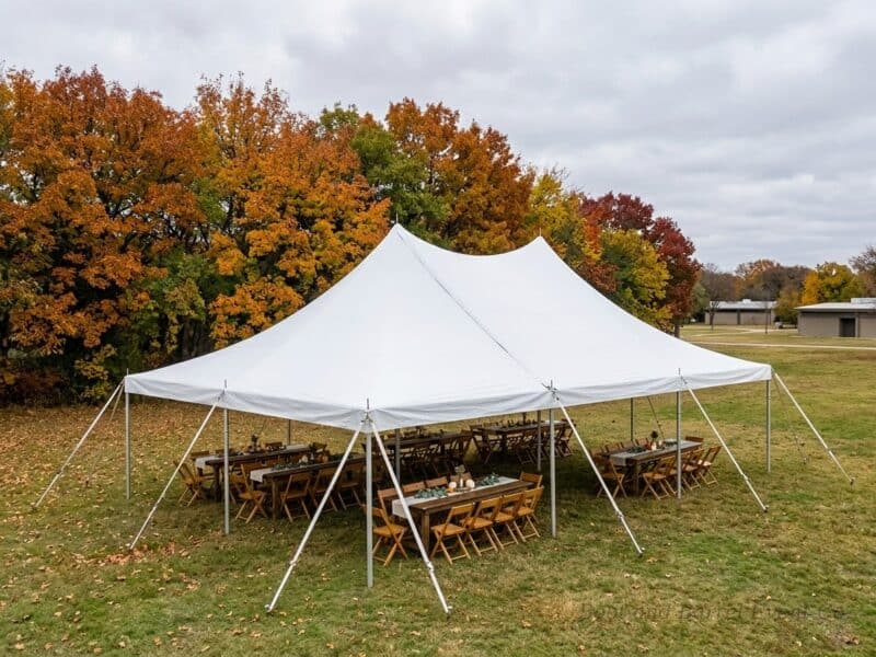 20x30 high peak pole tent rental in Rio Vista TX set up with farm tables and cross-back chairs for a fall outdoor reception