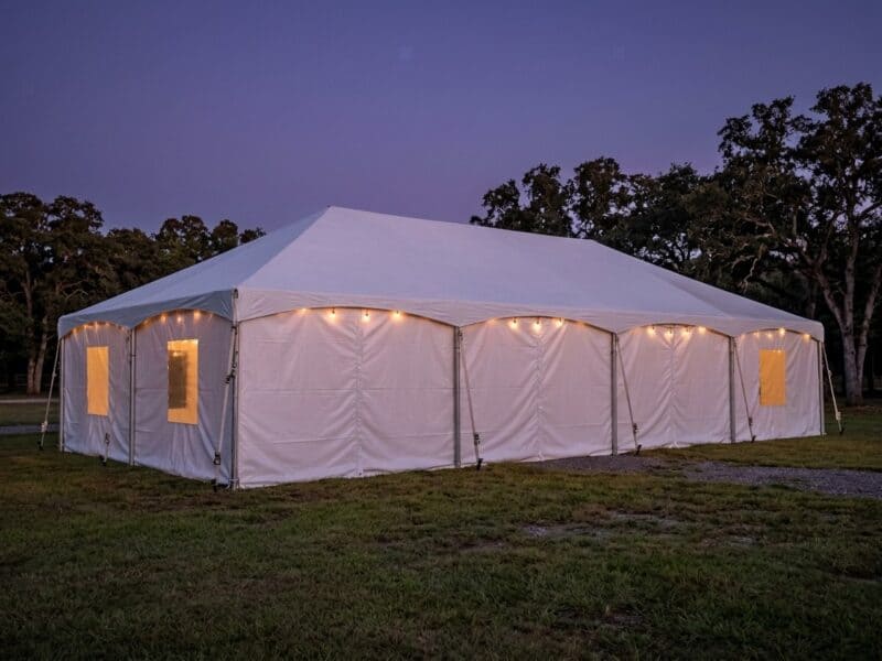 20x40 premium frame tent rental in Crowley TX with partial sidewalls set up beside a weathered gray barn on a summer day
