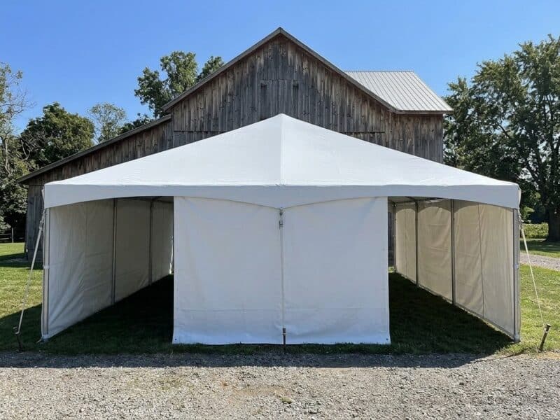 20x40 premium frame tent rental in Burleson TX with full white sidewalls set up beside a rustic red barn on a sunny day