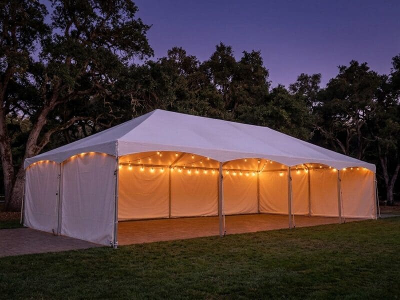20x40 premium frame tent rental in Benbrook TX with open front sidewalls string lights and a wood dance floor at dusk on a Texas ranch