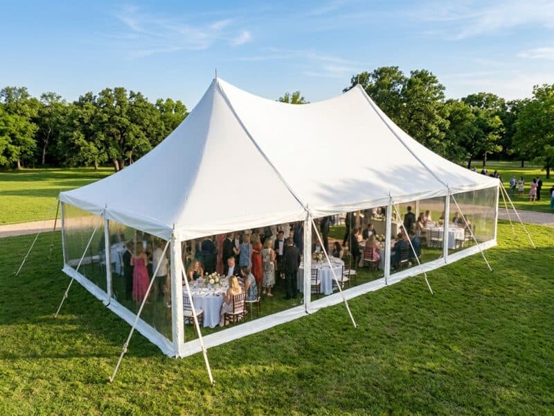 Aerial view of a 20x40 high peak pole tent rental in Benbrook TX with clear sidewalls and guests seated at round tables for an outdoor wedding reception