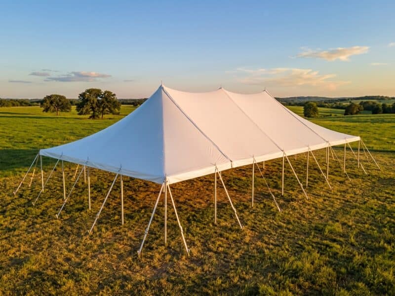 30x60 WIND pole tent open sides at golden hour on a North Texas ranch with green pasture and oak trees — Boot & Barrel Event Co. Mansfield TX