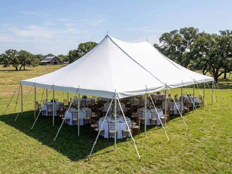 40x60 WIND pole tent open sides with round tables and cross back chairs set for a wedding reception on a Texas ranch with barn backdrop — Boot & Barrel Event Co. Midlothian TX