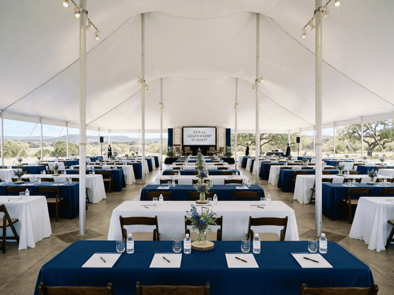 Banquet tables arranged for corporate conference event under tent in Texas