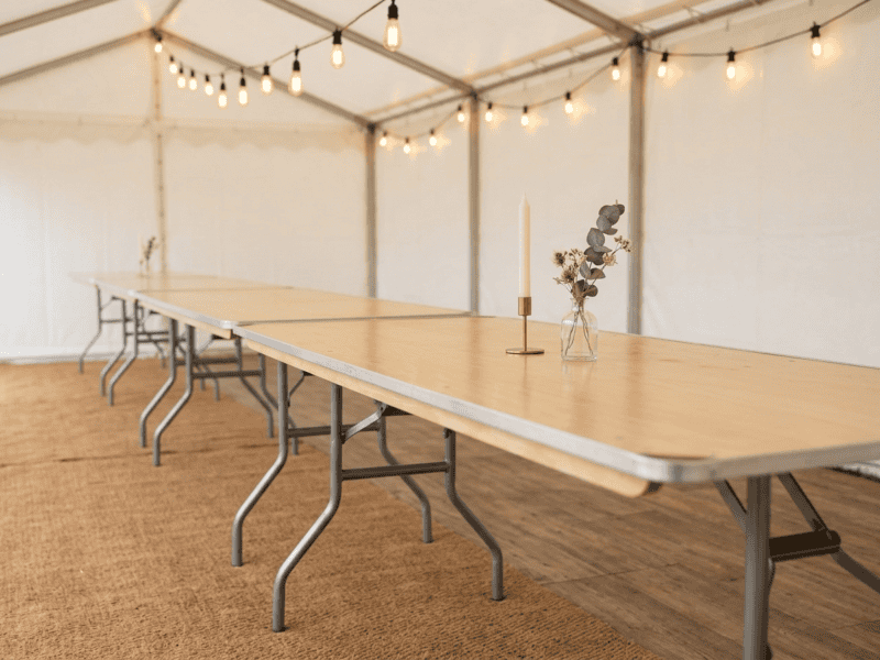 8 foot x 30 inch birchwood banquet table showing natural bare wood top with candle and bud vase inside tent in Crowley Texas