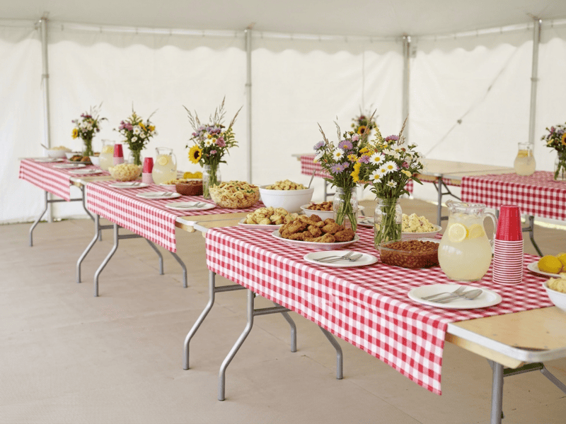 8 foot x 30 inch birchwood banquet table with red checkered linen for casual family reunion under tent in Mansfield Texas