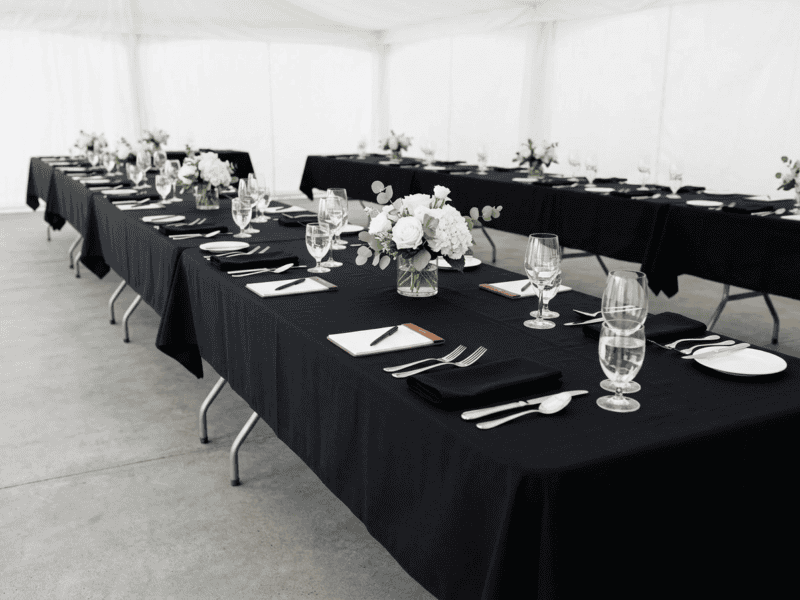 8 foot x 36 inch wide birchwood banquet table with black linen for corporate meeting under tent in Texas
