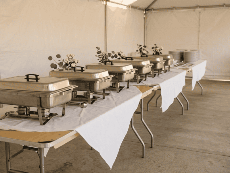 8 foot x 36 inch wide birchwood banquet table set up as buffet line with chafing dishes under tent in Texas