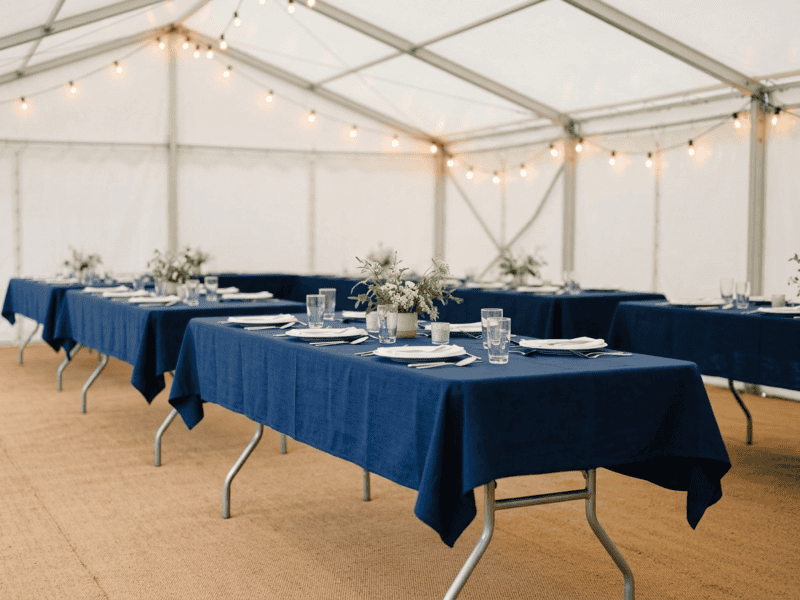 8 foot x 36 inch wide birchwood banquet table with navy linen for corporate event under tent in Texas