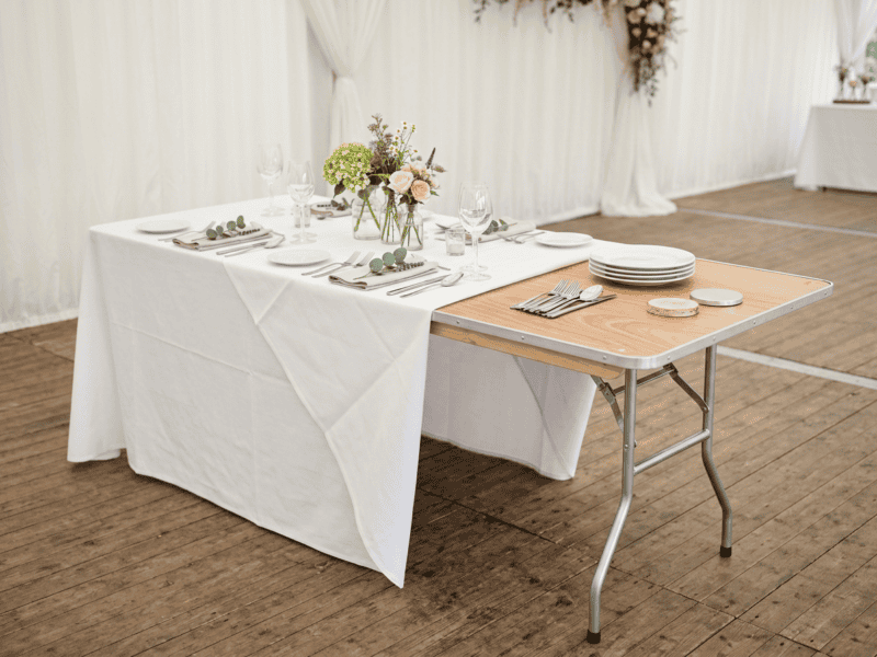 Birchwood banquet table half dressed with white linen showing wood top underneath
