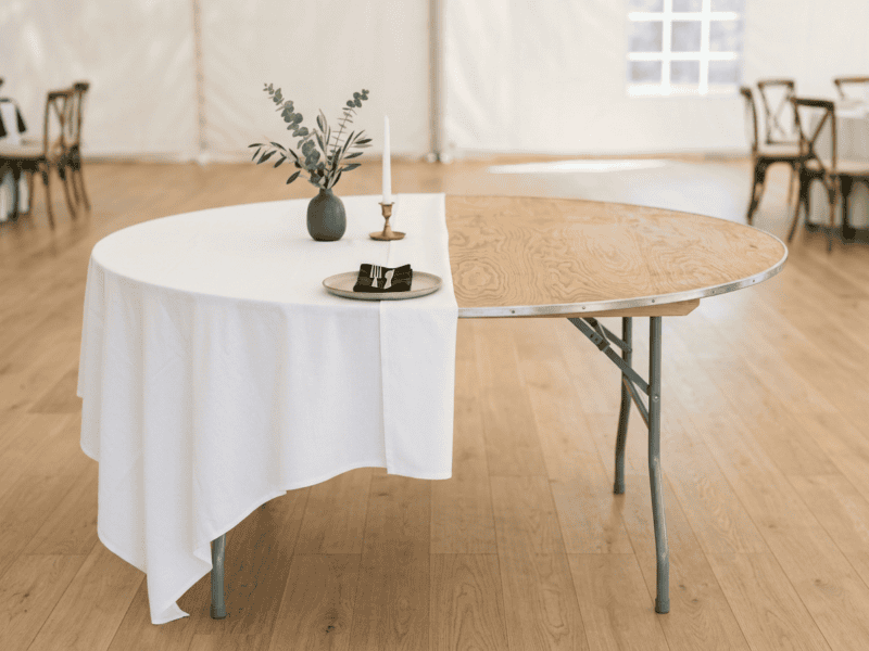 Birchwood banquet table half dressed with white linen showing wood top underneath