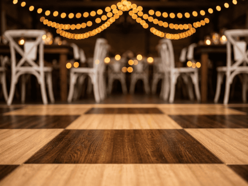 Close up of chestnut and fruitwood two-tone dance floor surface showing contrasting wood grain with elegant event setup in background — Boot & Barrel Event Co. Weatherford TX