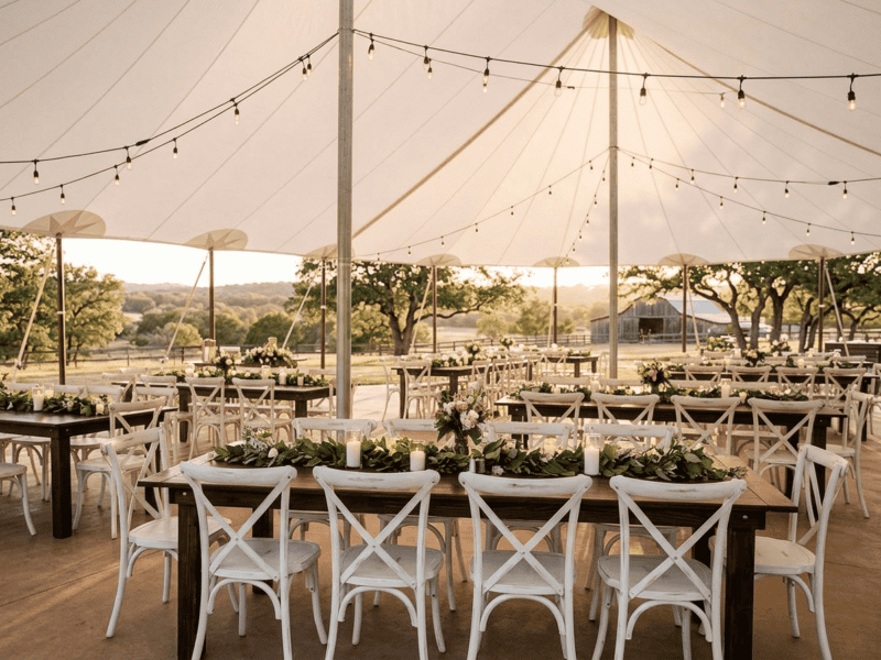 Distressed white cross-back chair at wedding reception under tent in Granbury TX — Boot & Barrel Event Co. rental