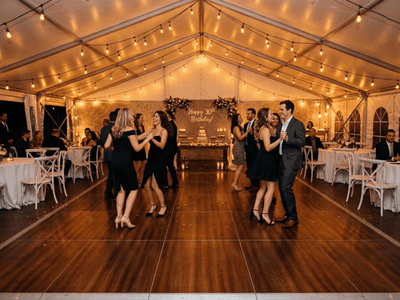 Fruitwood portable dance floor rental at an outdoor birthday party with white distressed chairs and string lights under white tent — Boot & Barrel Event Co. Fort Worth TX