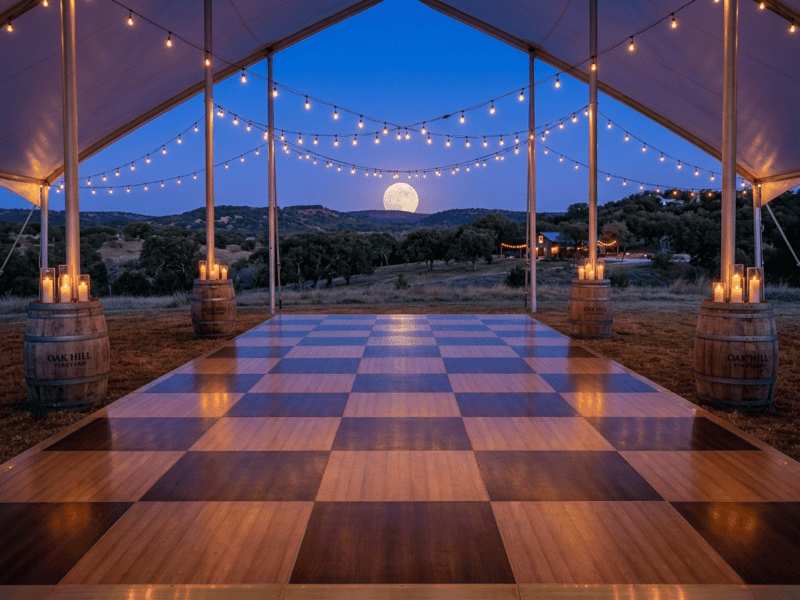 Chestnut and fruitwood dance floor rental at twilight reflecting warm Edison string lights with full moon over Texas hills — Boot & Barrel Event Co. Venus TX