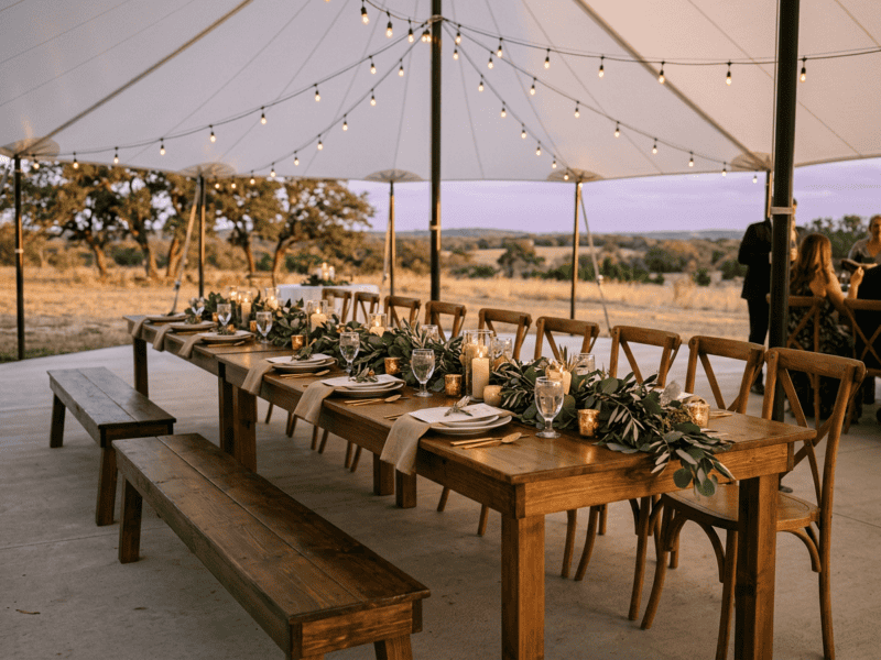 Mixed seating with rustic farm bench and cross-back chairs at wedding reception in Texas