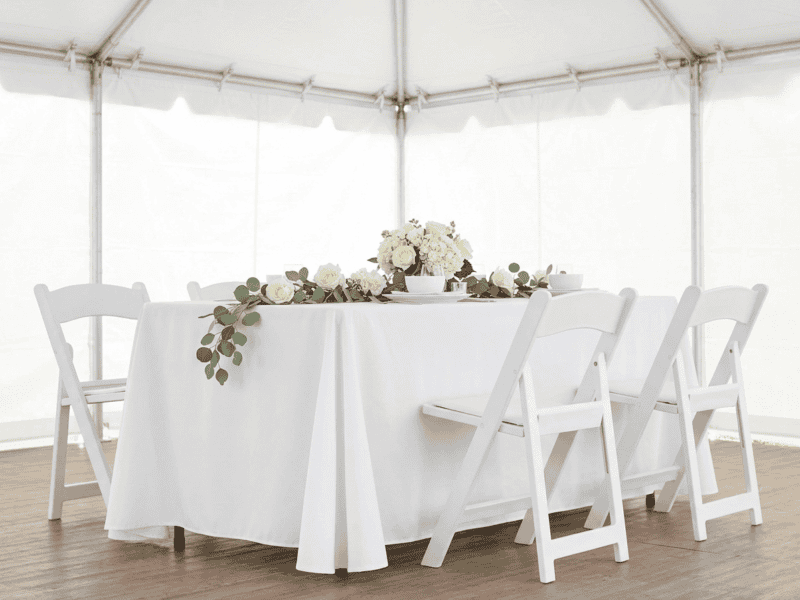 White folding chair paired with linen banquet table in Joshua TX — Boot & Barrel Event Co. rental