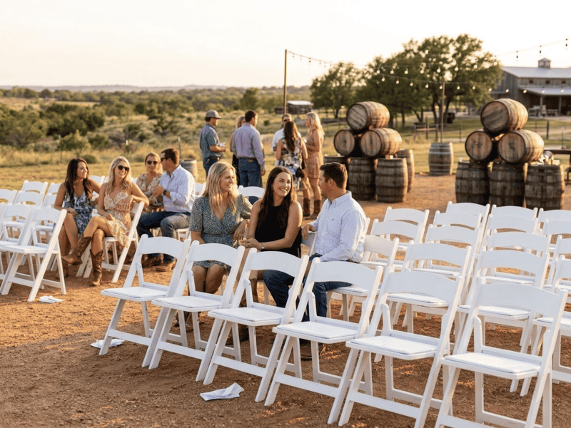 White folding chair at outdoor event with guests in Alvarado TX — Boot & Barrel Event Co. rental