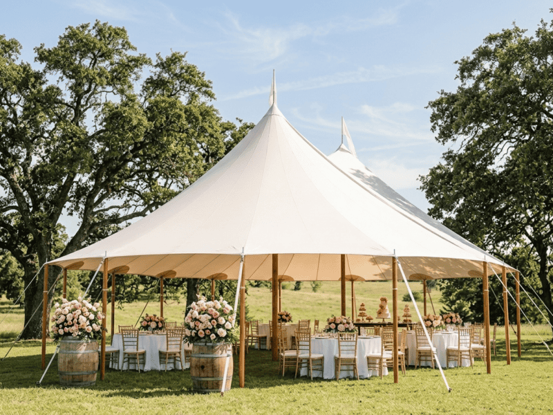 44x63 sailcloth tent bridal shower daytime with two peaks, pink floral barrel decor, gold chiavari chairs and blue Texas sky