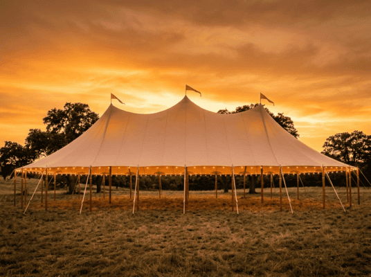 44x83 sailcloth tent with three soaring peaks photographed from the side in open Texas pasture at golden hour, Boot & Barrel Event Co. Cleburne TX